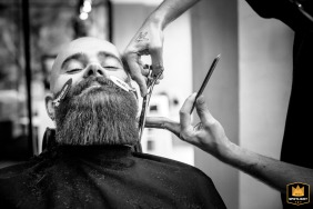 Stylish groom receiving beard trimming at a barbershop in Meylan, France.